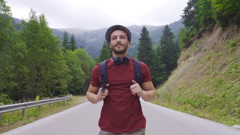 un joven feliz caminando por un camino de asfalto en el bosque.