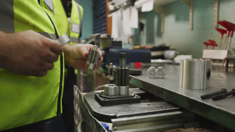 Close-up-detail-of-hands-of-a-Caucasian-male-factory-worker-standing-at-a-workbench-and-working-on-a