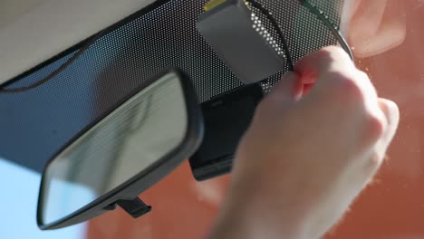 manos conectando cables a la cámara delantera del grabador de automóvil conectado al parabrisas