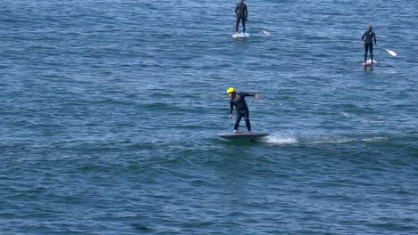 man on efoil with people paddleboarding in the ocean