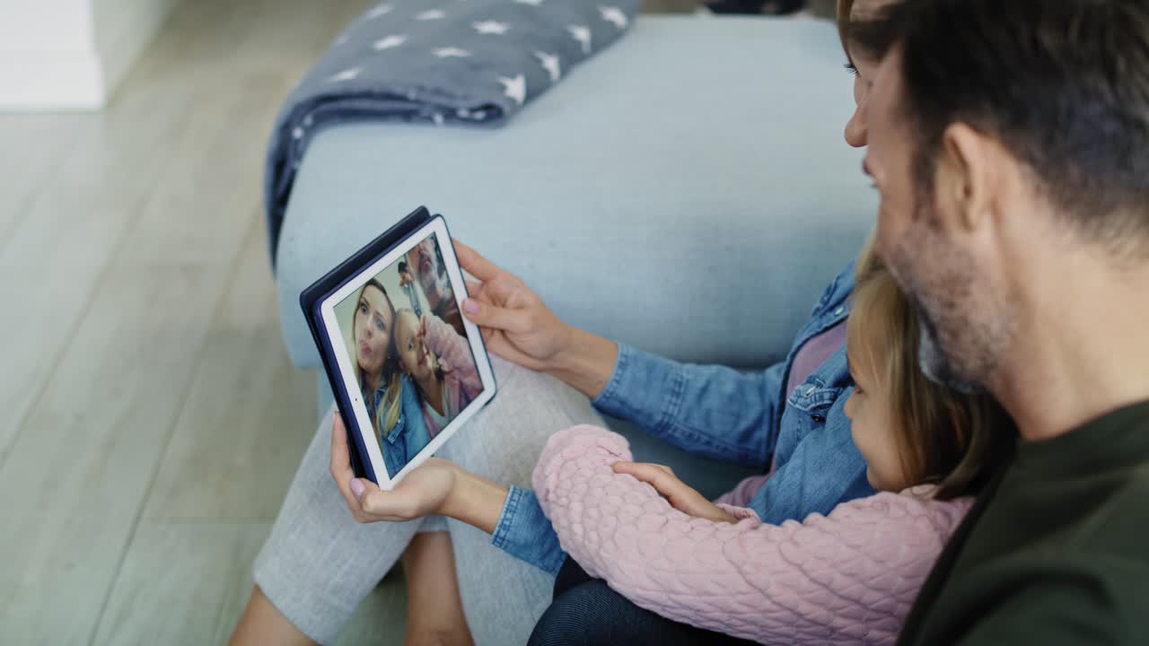 padres con su hija viendo fotos en la tableta
