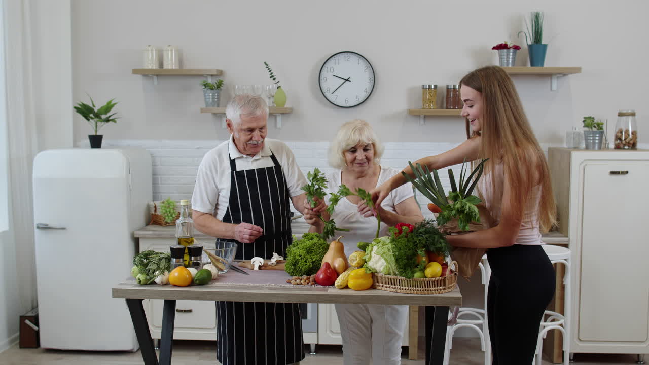 Älteres Ehepaar in der Küche erhält Gemüse vom Enkelkind. Rohkost, gesunde Ernährung