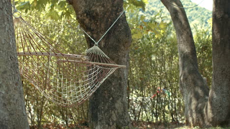 calm and peaceful hammock swinging with gentle breezing wind, hung between trees in slowmo