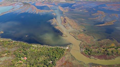 lagoon with land surrounded by mud and shallow water, bordered by a sandy beach and trees from the adriatic sea in albania