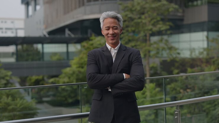 Confident Asian Businessman Standing with Arms Crossed and Smiling Outdoors
