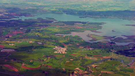 Explore-El-Encantador-Pueblo-Colorido,-La-Vista-Aérea-Cubierta-De-Granjas-Verdes,-Calles-Estrechas-Y-Un-Lado-Del-Río-Serpenteante-Del-Valle