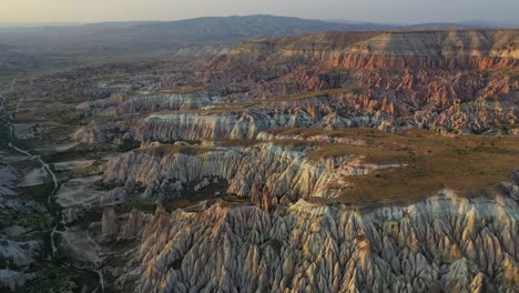 Cappadocia-landscape-with-tuff-stone-formations-after-sunrise,-aerial-panning-left