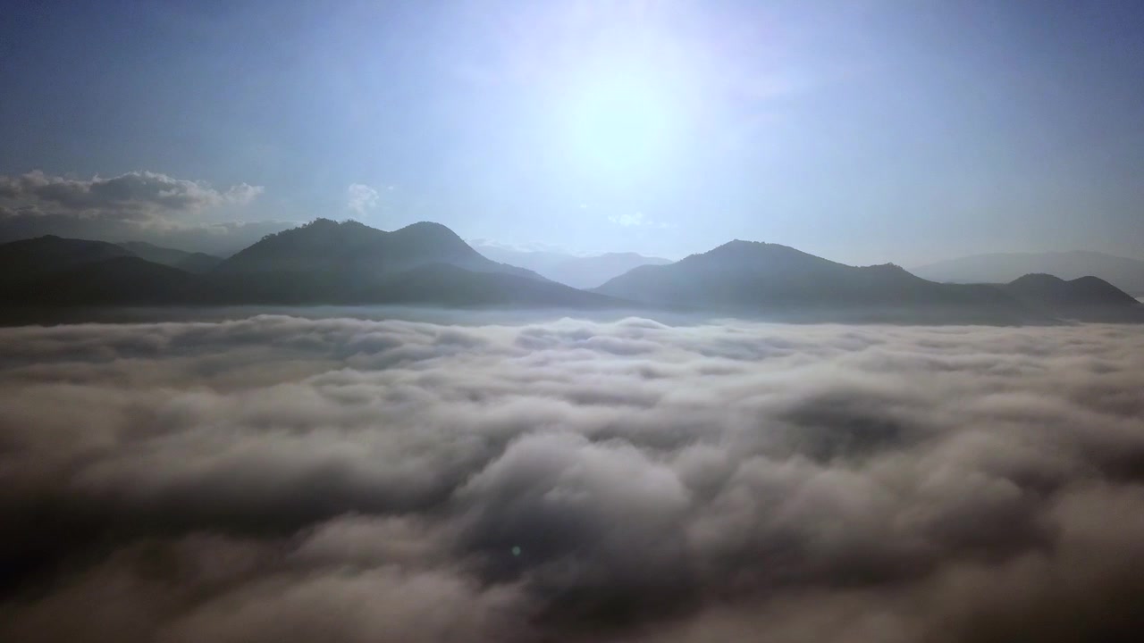Elevating above the clouds in the morning. Beautiful mountains in the background.