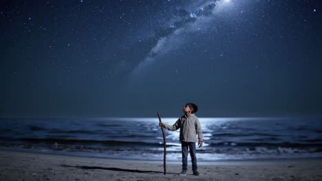 boy gazing at the starry night sky on a beach
