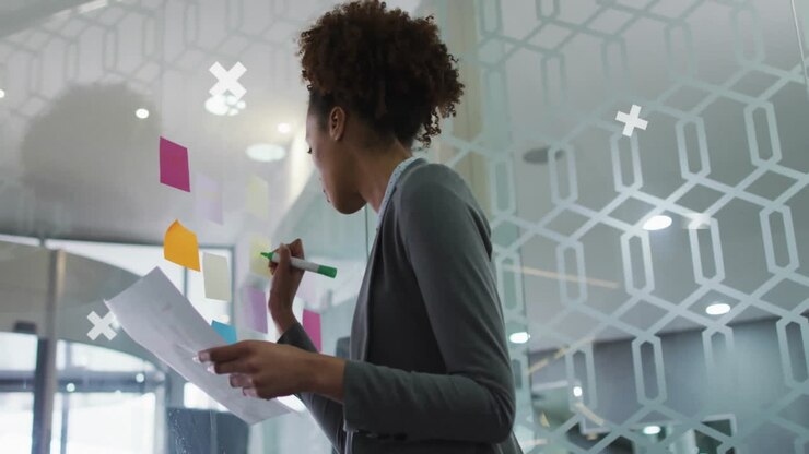 Woman writing on sticky notes in business office, with floating bar charts and data icons