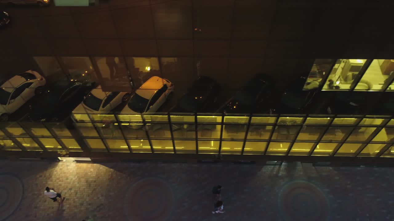 vista exterior de 4k del edificio del distrito comercial, centro comercial con ventanas de espejo de pared por la noche o por la noche. reflejo de la ciudad, la gente, los coches en las paredes espejadas. cámara de dron moviéndose. personas que trabajan dentro