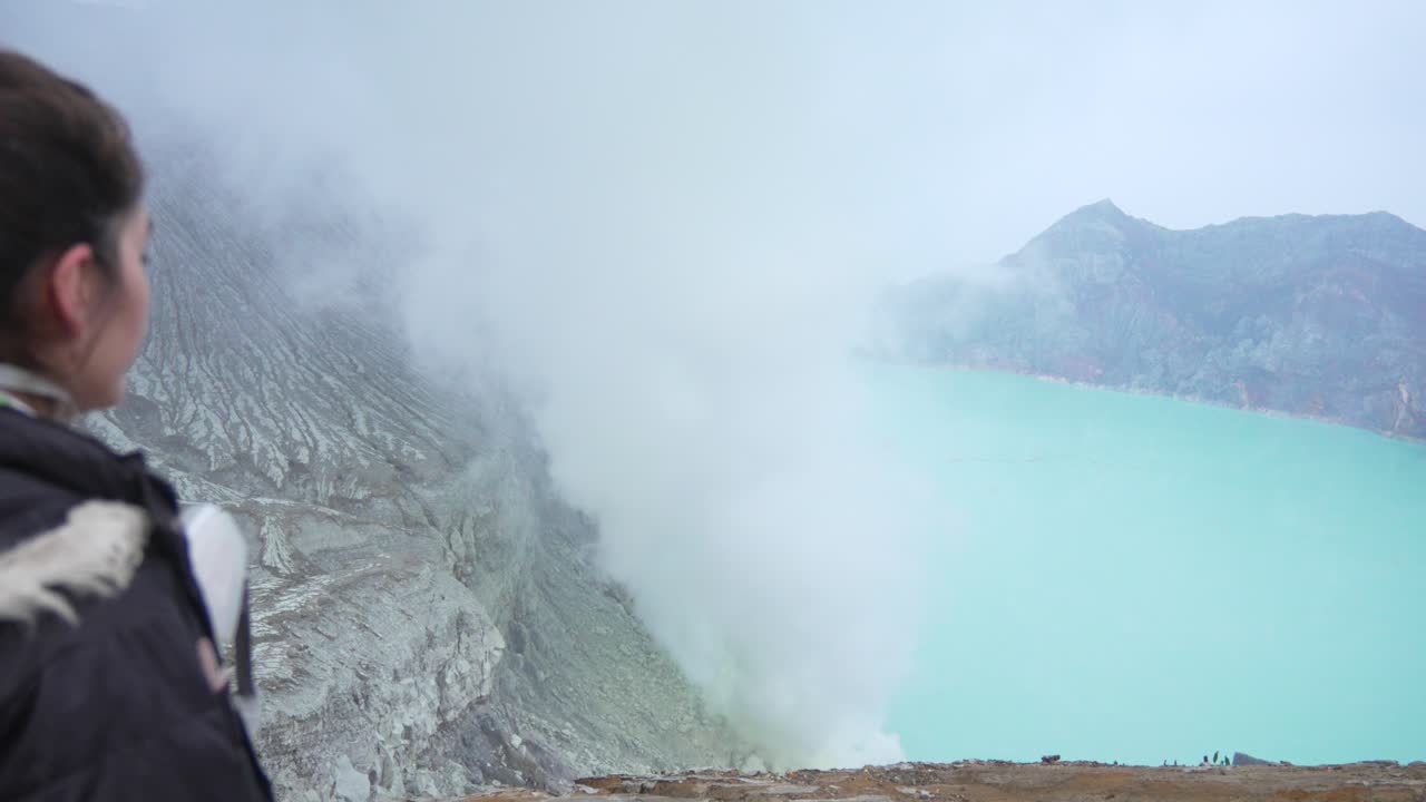 Young woman tourist Ijen Volcano caldera crater lake acidic water Java island Indonesia