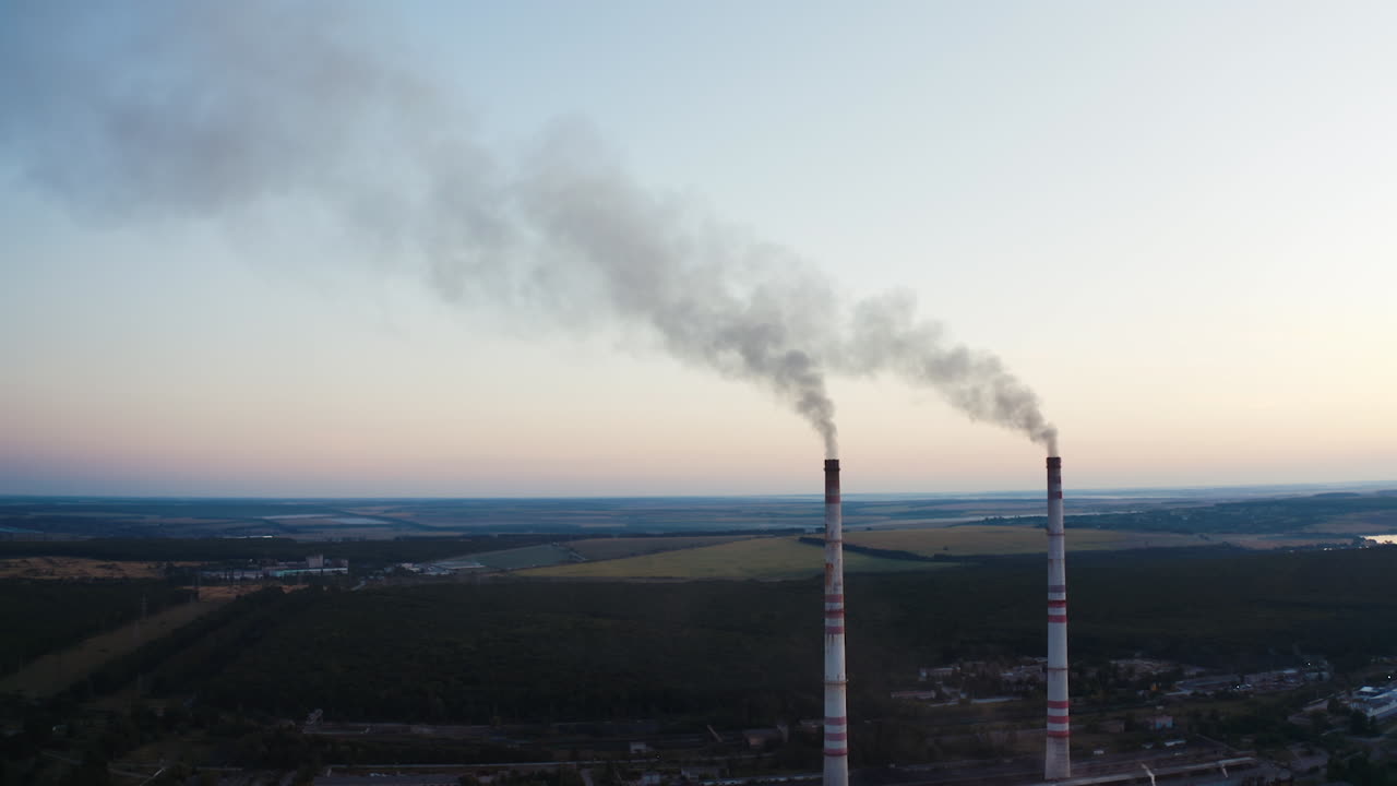 Two pipes with smoke on the beautiful landscape of nature. White smoke pouring out from industrial pipes in the air in the evening.