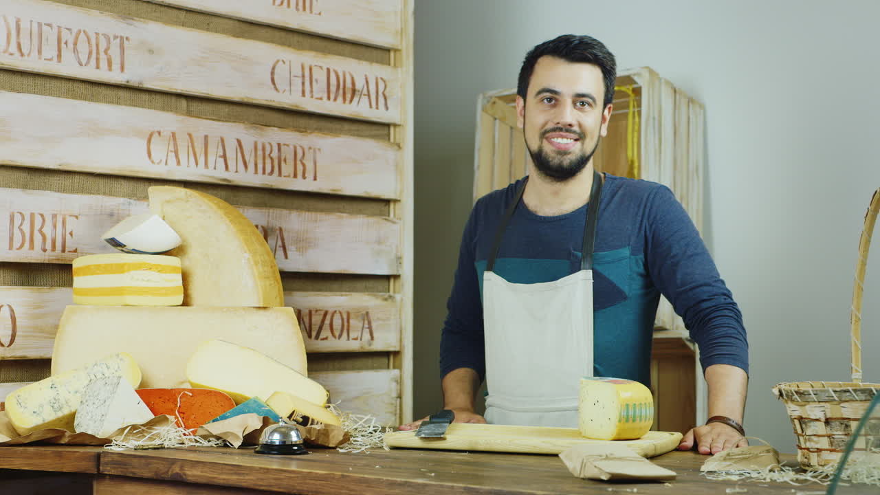 retrato del amable vendedor en la tienda de queso que mira a la cámara sonriendo