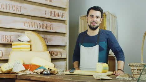 Portrait-Of-The-Friendly-Salesperson-In-The-Store-Cheese-He-Looks-Into-The-Camera-Smiling