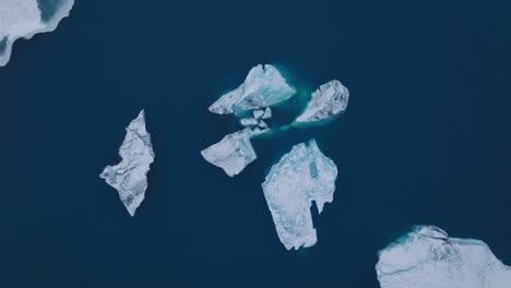 Aerial-top-view-over-icebergs-in-the-glacial-water-of-Jokulsarlón-lake,-in-Iceland,-during-winter