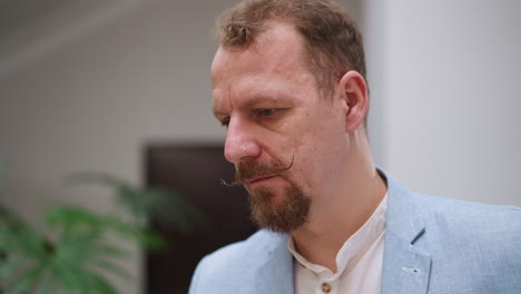 worried man stands in business center hall closeup. mature businessperson with handlebar moustache thinks about difficult meeting. corporate employee