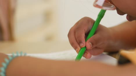 close-up of a child's hand drawing with a green marker