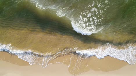 tropical beach aerial view, top view of waves break on tropical white sand beach. sea waves seamless loop on the beautiful sand beach.