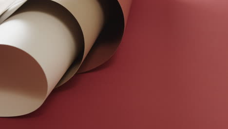 Close-up-of-three-shades-of-brown-rolled-papers-on-red-background-with-copy-space-in-slow-motion