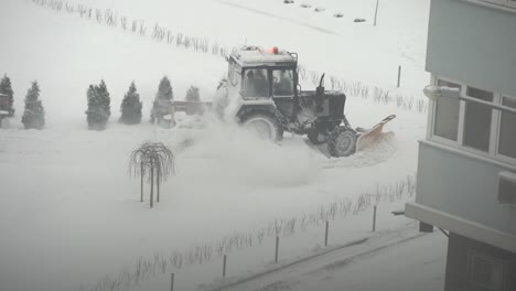 tractor-excavator removes snow in the city yard. work of public utilities