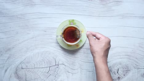 hand reaching for tea bag in teacup