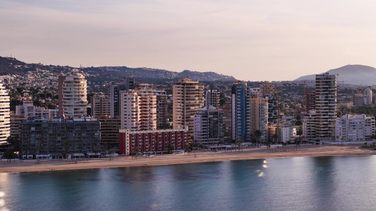 Paesaggio urbano di Calpe con grattacieli e una spiaggia sabbiosa in riva al mare.