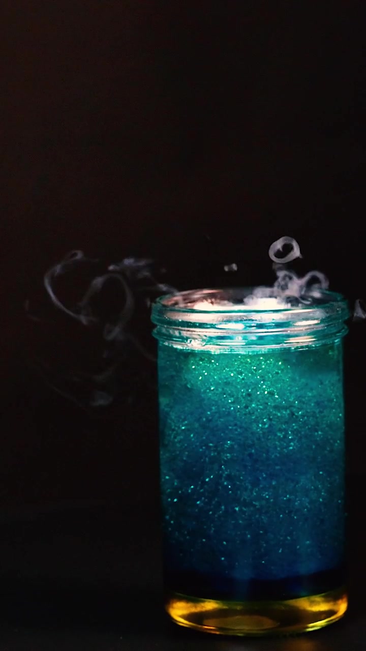 Un becher con ghiaccio secco crea un effetto fumoso e gorgogliante in un ambiente scuro, mostrando una reazione chimica