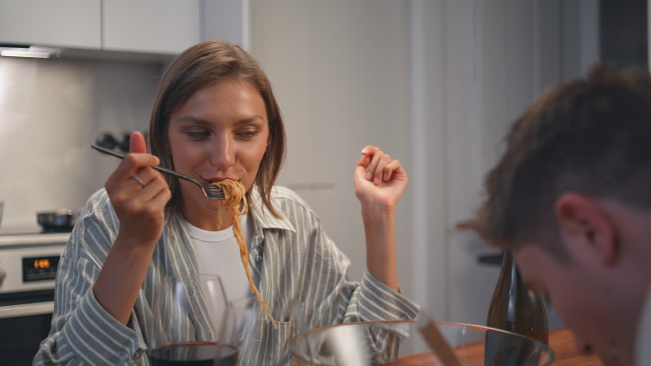 Smiling girlfriend eating date evening. Romantic couple enjoying pasta dinner