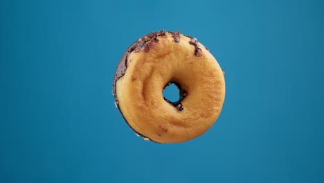 donut delicioso aislado girando en el fondo azul. donut de chocolate.