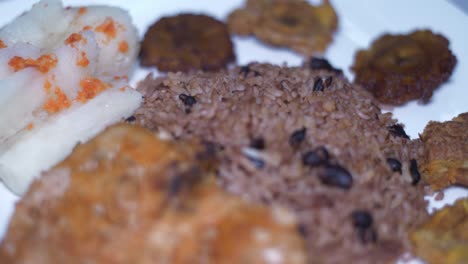 cuban plate of traditional food, rice and beans boiled yuca, smashed fried bananas and chicken steak rotating on a turning table