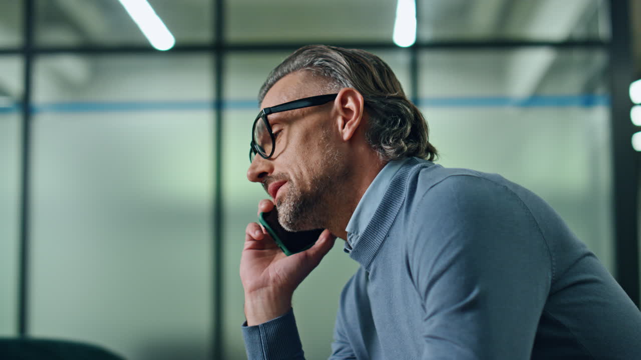Uomo d'affari fiducioso che parla al cellulare all'interno di un ufficio. Manager che telefona.