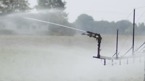 Watering-the-fields-with-an-automatic-watering-machine,-midday