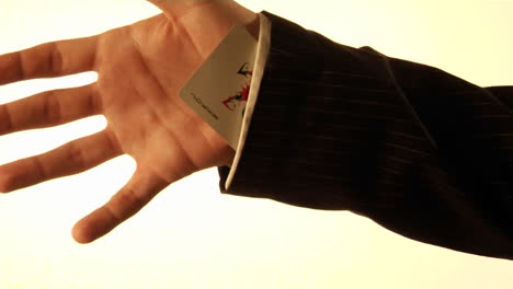un hombre mete una carta de juego en la manga de su camisa
