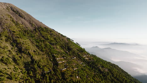 drone shot of shanty houses near summit of inactive acatenango volcano in guatemala during sunrise