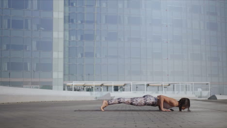 girl doing upward facing dog pose outdoors. woman exercising yoga on city street