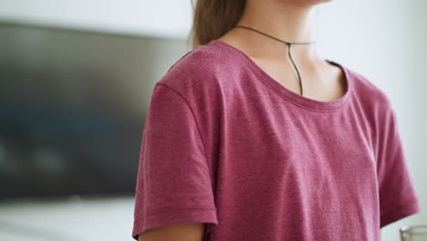 young girl walking while holding a coffee cup with focused expression, wearing a pink top and a rope tied around her neck, captured in soft light for a calm, contemplative moment