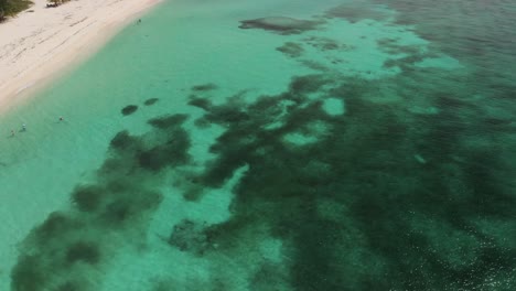 Tilt-up-shot-revealing-beautiful-Mexican-island-through-turquoise-water-and-revealing-white-sand-beach-alongside-seashore