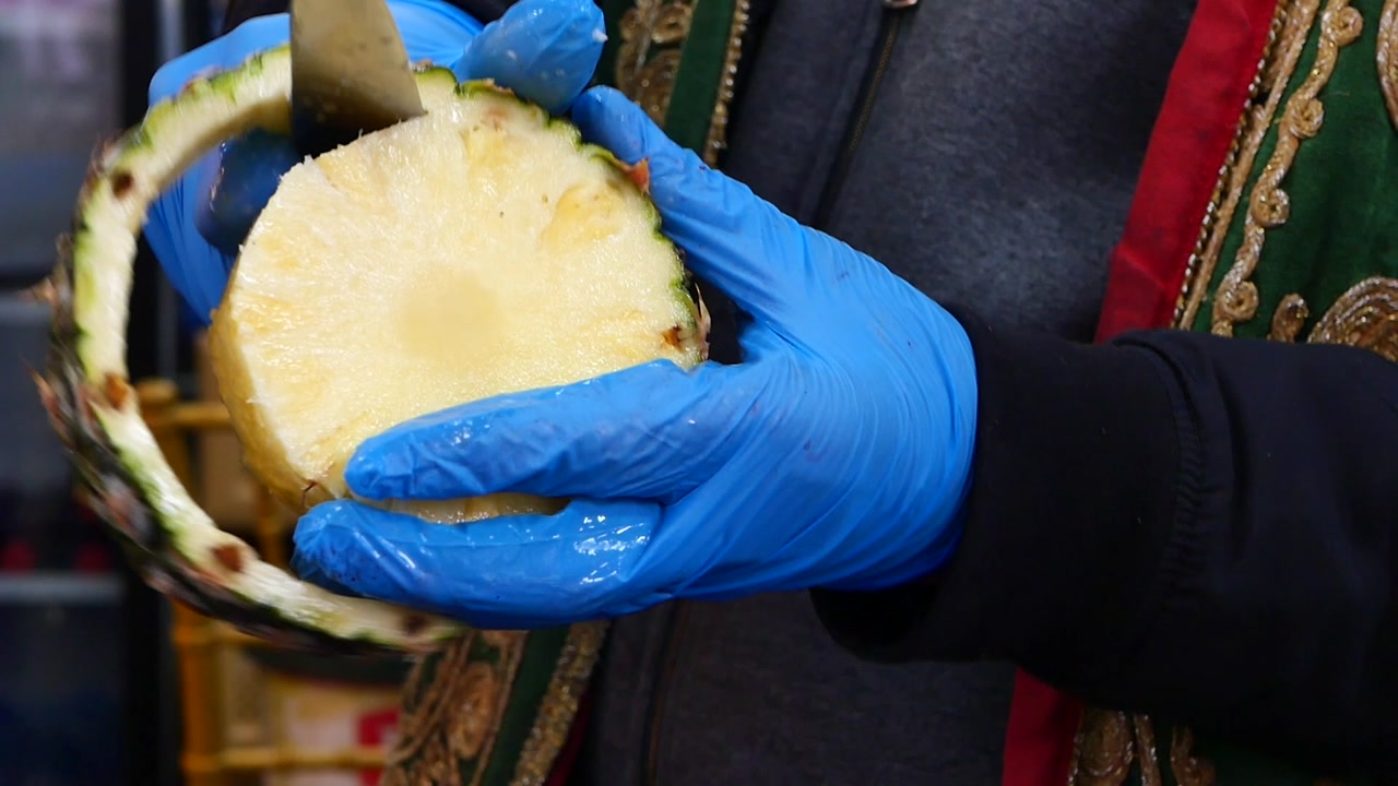 Close-up of Hands in Blue Gloves Peeling a Fresh Pineapple