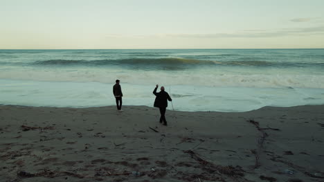 silhouette of two people admiring the power of nature stormy ocean waves