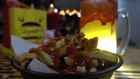 disparo estático de una porción de papas fritas con ketchup con una mano recogiendo una