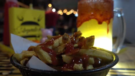 static shot of a portion of fries with ketchup with a hand picking one up