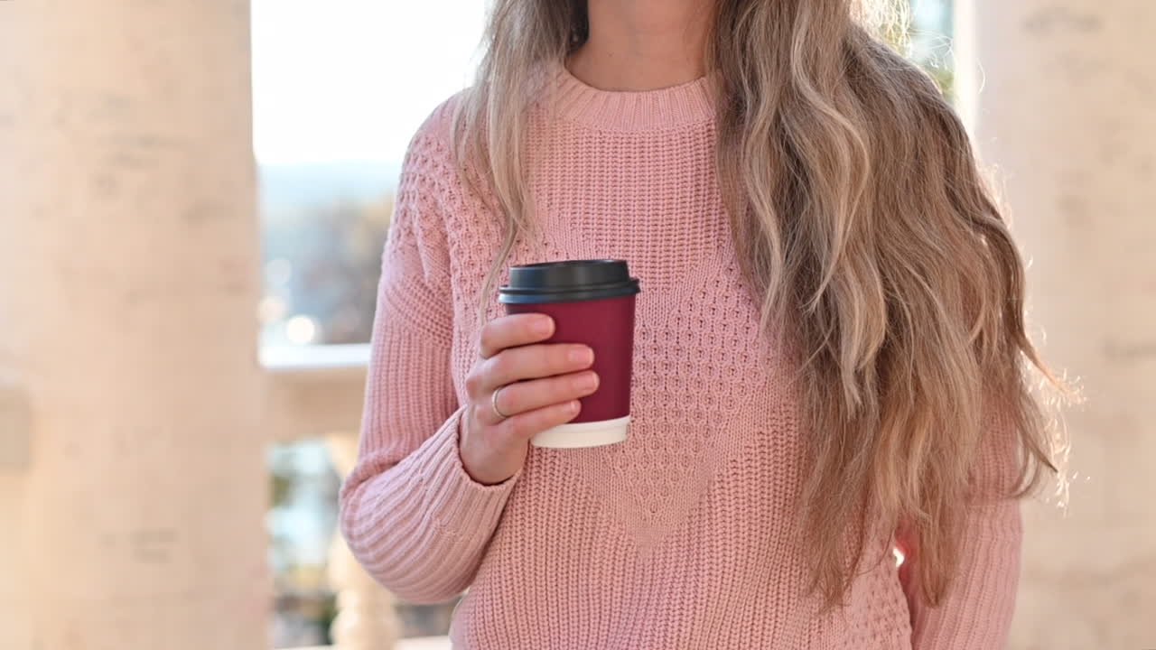 Woman drinking coffee and smiling in a park at sunset