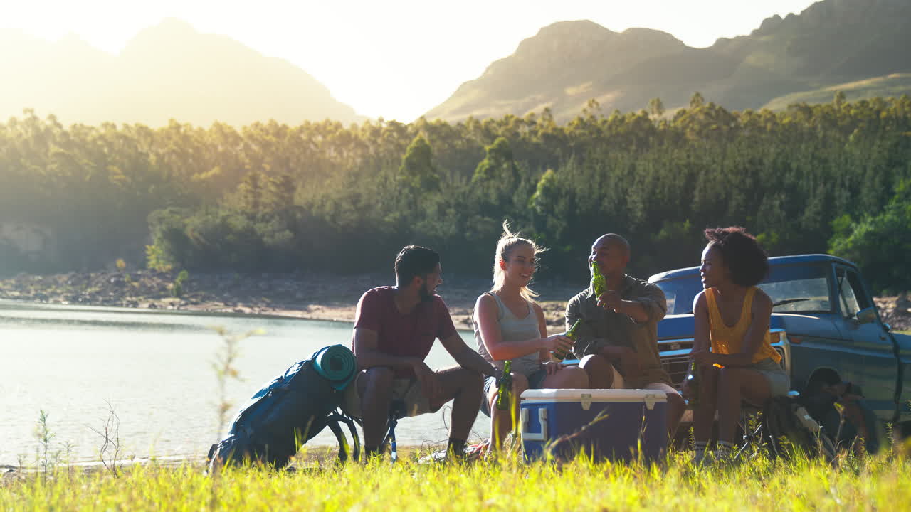 호수에서 냉장고에서 맥주를 마시는 도로 여행에 픽업 트럭으로 배을 가진 친구 그룹