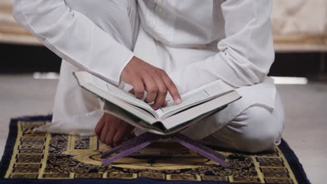 primer plano de un hombre indio leyendo un libro del corán en casa
