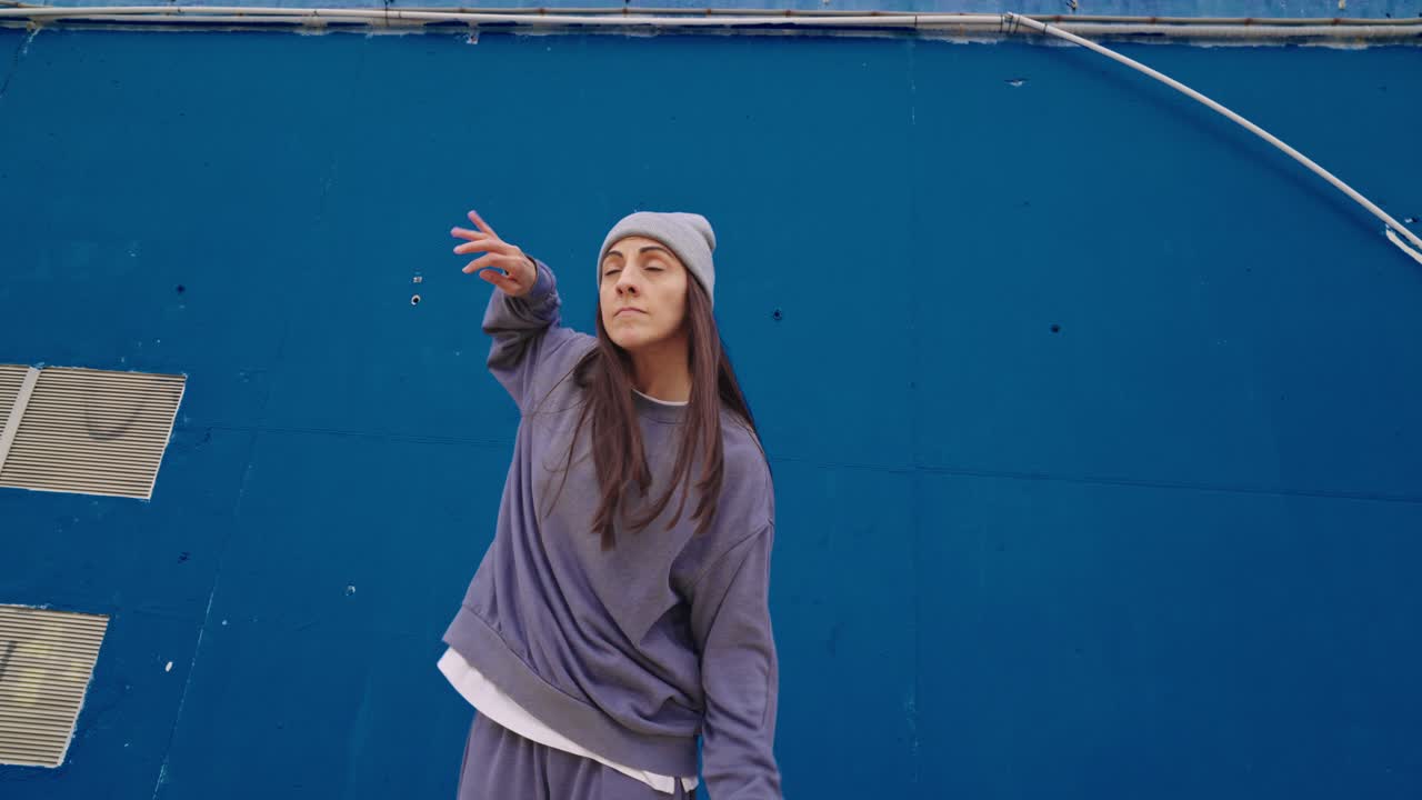 Woman dancing in front of blue wall