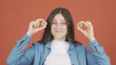 mujer joven sosteniendo bitcoin y mostrándolo.