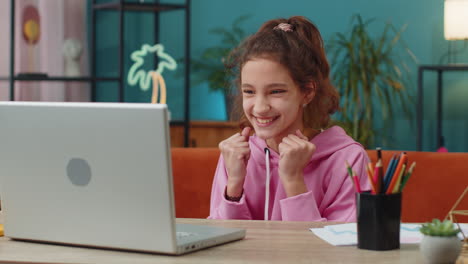 school girl using laptop celebrating victory at online lottery successful passing of education exam