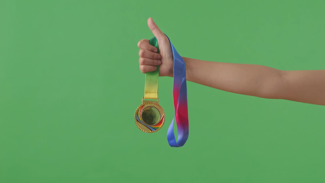 medalla de oro en la mano. fondo de pantalla verde