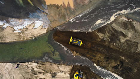 static top-down view of bulldozer and excavator moving sediment and dirt for pond channel diversion